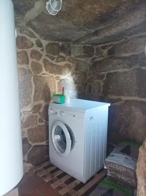 a washer and dryer in a room with a stone wall at Casa do Xurés in Maus de Salas