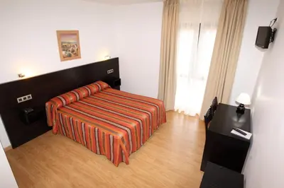 a hotel room with a bed with an orange blanket at Hotel Amenal in Amenal