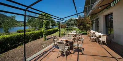 a patio with tables and chairs and a view of a river at Laias Caldaria hotel y Balneario in Laias