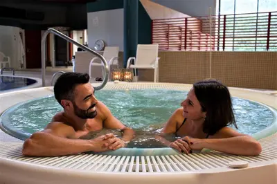 a man and a woman sitting in a hot tub at Laias Caldaria hotel y Balneario in Laias