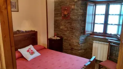 a bedroom with a bed with a pillow and a window at Apartamentos Los Castros in San Tirso de Abres