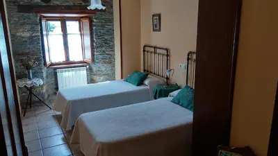 a room with two beds and a window at Apartamentos Los Castros in San Tirso de Abres