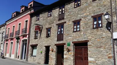 a large brick building with brown doors and windows at Apartamentos Los Castros in San Tirso de Abres