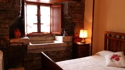 a bedroom with a bed and a window with a cross at Apartamentos Los Castros in San Tirso de Abres