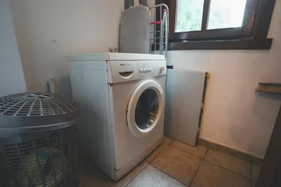 a washing machine in a room with a trash can at HolaCamp Camino in O Pino