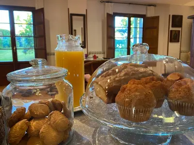 a table with a plate of muffins and a jar of orange juice at Las Casonas de Avellaneda in Navia