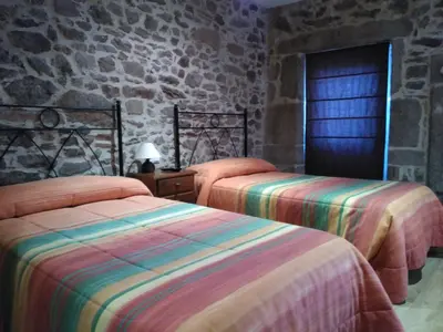 a bedroom with two beds and a stone wall at Casa dos Eiriz in Souto