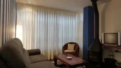 a living room with a couch and a chair and a television at Apartamentos Lagos de Saliencia in Saliencia