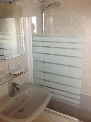 a white bathroom with a sink and a shower at Hotel Los Olmos in Lugo