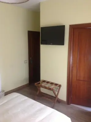 a bedroom with a bed and a flat screen tv on the wall at Hotel Los Olmos in Lugo