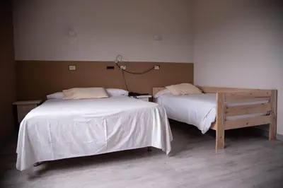 a room with two beds and a lamp on the wall at Hotel Los Olmos in Lugo