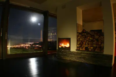 a room with a fireplace with a view of a city at night at Hotel Rural 3 Cabos in El Vallin