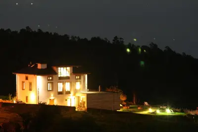 a house lit up at night with lights at Hotel Rural 3 Cabos in El Vallin