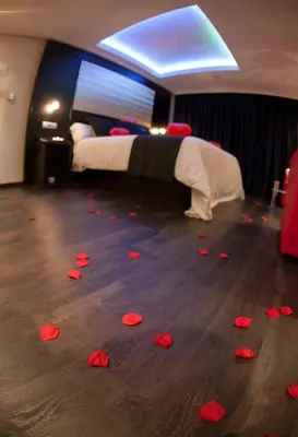 a room with a bed and red rose petals on the floor at Motel Paraiso in Outeiro de Rei