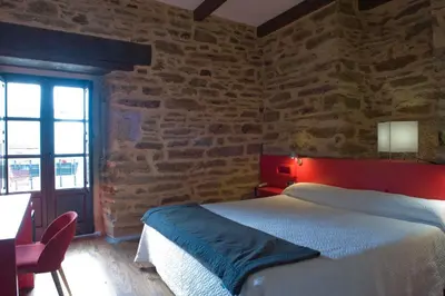 a bedroom with a bed and a brick wall at Posada Real de Las Misas in Puebla de Sanabria