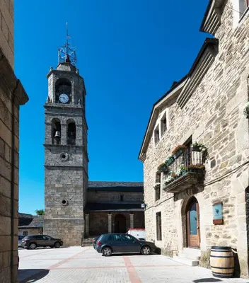 a clock tower with a car parked in front of a building at Posada Real de Las Misas in Puebla de Sanabria
