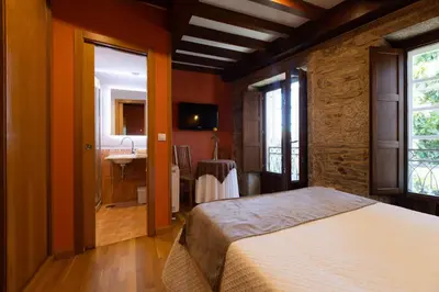 a bedroom with a large bed with orange walls at PR Badalada in Santiago de Compostela
