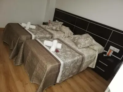 two beds in a room with white candles on them at Pension Orois in Melide