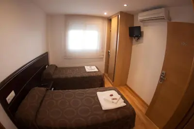 a small room with two beds and a window at Pension Orois in Melide