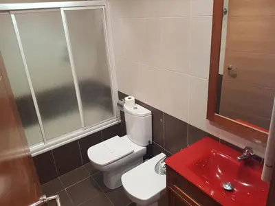 a bathroom with a white toilet and a red sink at Pension Orois in Melide