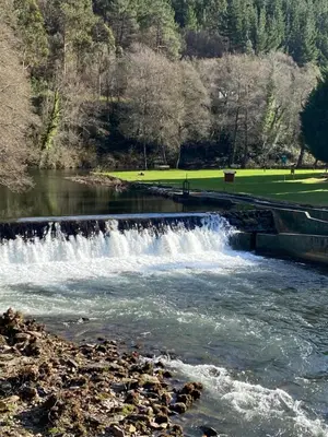 a waterfall in a river with a bridge at Hotel Mirador de Barcia in Ribeira de Piquin