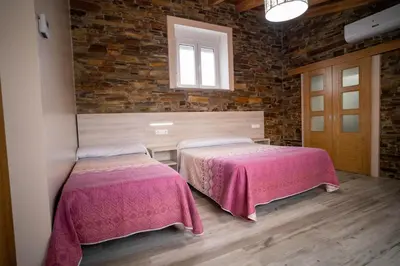 two beds in a room with a brick wall at El Pinar in Ribadeo