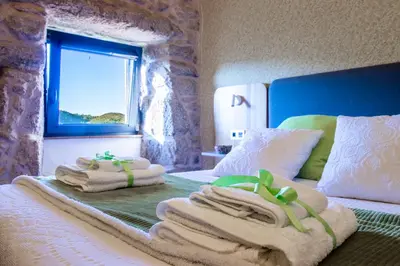 a bedroom with towels on a bed with a window at Casa Costiña in Cotobade