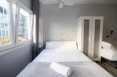 a white bed in a room with a window at Pensión Caldas in Caldas de Reis