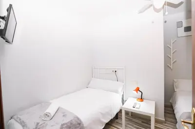 a white bedroom with a bed and a table at Pensión Caldas in Caldas de Reis