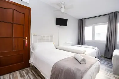a hotel room with two beds and a tv at Pensión Caldas in Caldas de Reis