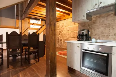 a kitchen with an oven and a dining room with a table at Loft Medieval in Ribadavia