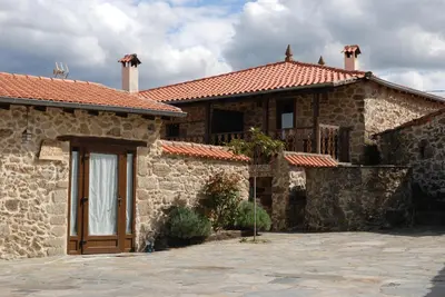 a stone house with a wooden door and a balcony at Complejo rural Aira Sacra-Ribeira Sacra in Vilamelle