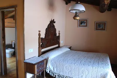 a bedroom with a bed with a wooden head board at Complejo rural Aira Sacra-Ribeira Sacra in Vilamelle