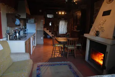 a living room with a fireplace and a kitchen at Complejo rural Aira Sacra-Ribeira Sacra in Vilamelle