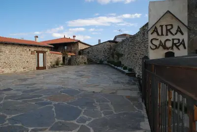 a stone walkway next to a building with a sign on it at Complejo rural Aira Sacra-Ribeira Sacra in Vilamelle