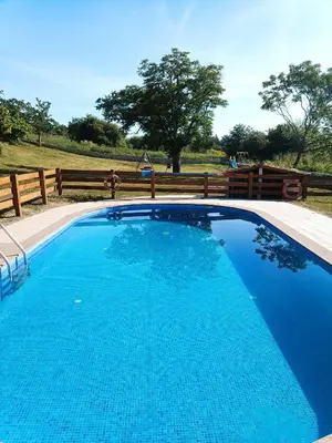 a large blue swimming pool next to a wooden fence at Casa dos Muros turismo rural y actividades en la Ribeira Sacra in Pantón