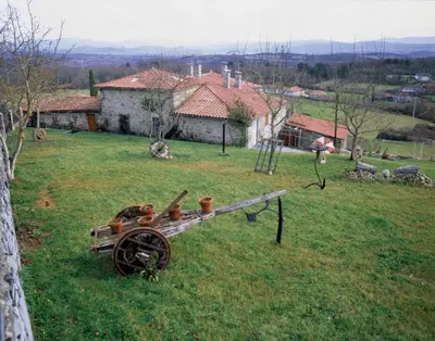 a field with an old wheel in the grass at Casa dos Muros turismo rural y actividades en la Ribeira Sacra in Pantón