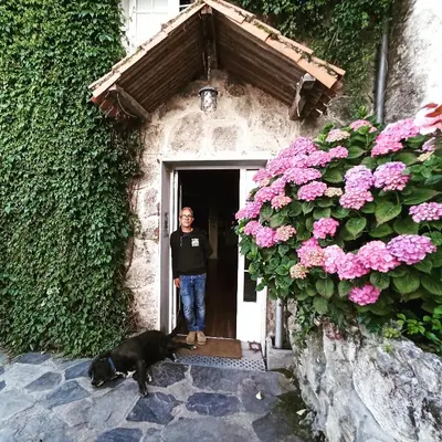 a man standing in the doorway of a house with a dog at Casa dos Muros turismo rural y actividades en la Ribeira Sacra in Pantón