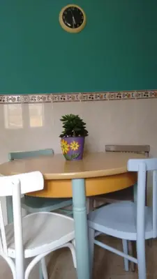 a table with two chairs and a clock on a green wall at Casa fonte da pena in Rinlo
