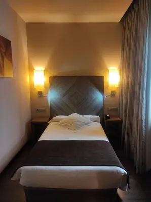 a bedroom with a large bed with two lights on it at Hotel Aroi Ponferrada in Ponferrada