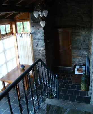 a room with a staircase with a wooden table and windows at Casa dos Pedrouzos in Doncos