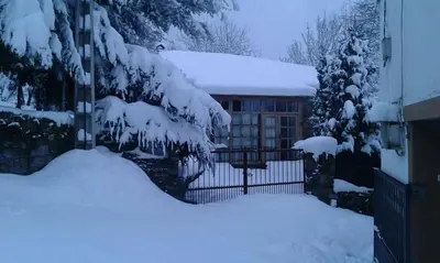 a house with a fence covered in snow at Casa dos Pedrouzos in Doncos