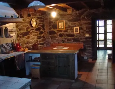 a kitchen with a counter and a stone wall at Casa dos Pedrouzos in Doncos