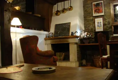 a living room with a table and a fireplace at Casa dos Pedrouzos in Doncos