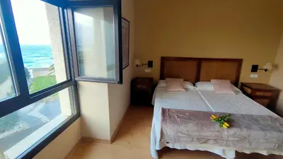 a bedroom with a bed and two large windows at Hotel Balcón de San Bartolo in Barreiros