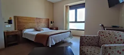 a bedroom with a bed and a chair and a window at Hotel Balcón de San Bartolo in Barreiros