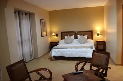 a bedroom with a bed and two chairs and a table at Hotel Balcón de San Bartolo in Barreiros