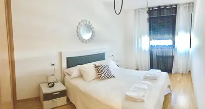 a white bedroom with a bed and a window at Alojamiento La Rosaleda in Ponferrada
