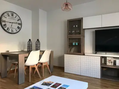 a living room with a table and a clock on the wall at Alojamiento La Rosaleda in Ponferrada
