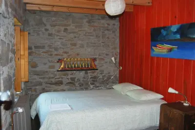 a bedroom with a bed and a stone wall at MIL MADREÑAS ROJAS in Salientes